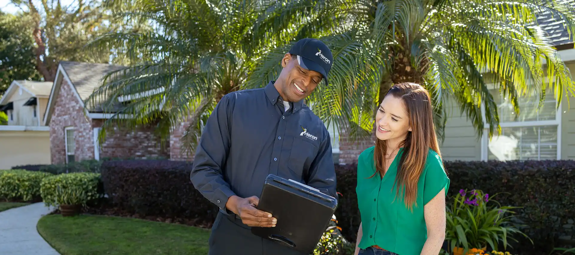 Pest control technician with customer outside residential home