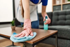 A Florida homeowner wiping down their coffee table after spraying it with cleaning solution